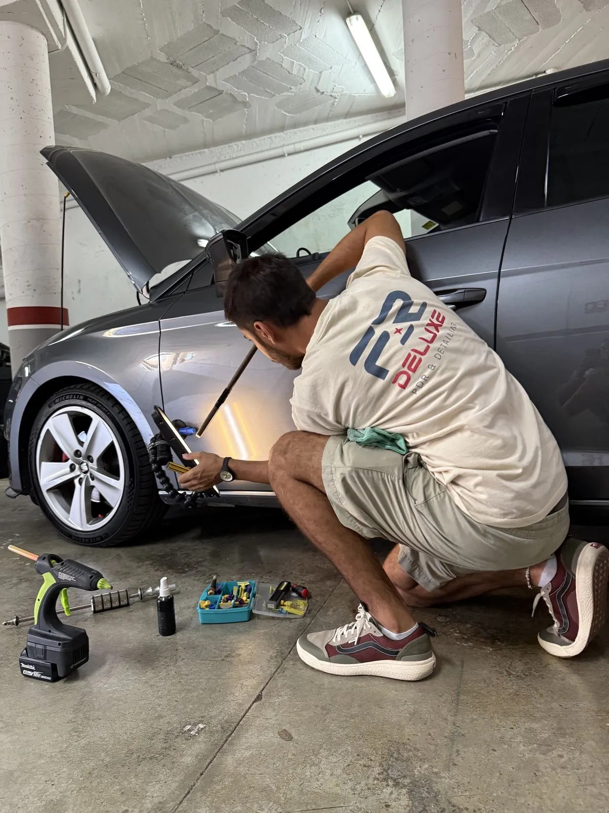 Federico trabajando con varilla PDR y lámpara LED reparando una abolladura en un coche en Barcelona